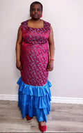 Plus size woman wearing a red and blue patterned dress with ruffled bottom section against a plain background
