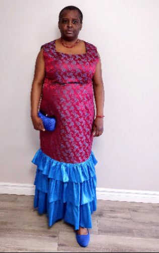 Plus size woman wearing a red and blue patterned dress with ruffled bottom section against a plain background