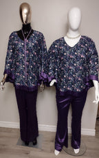 Two mannequins wearing matching floral tops and purple pants against a plain background